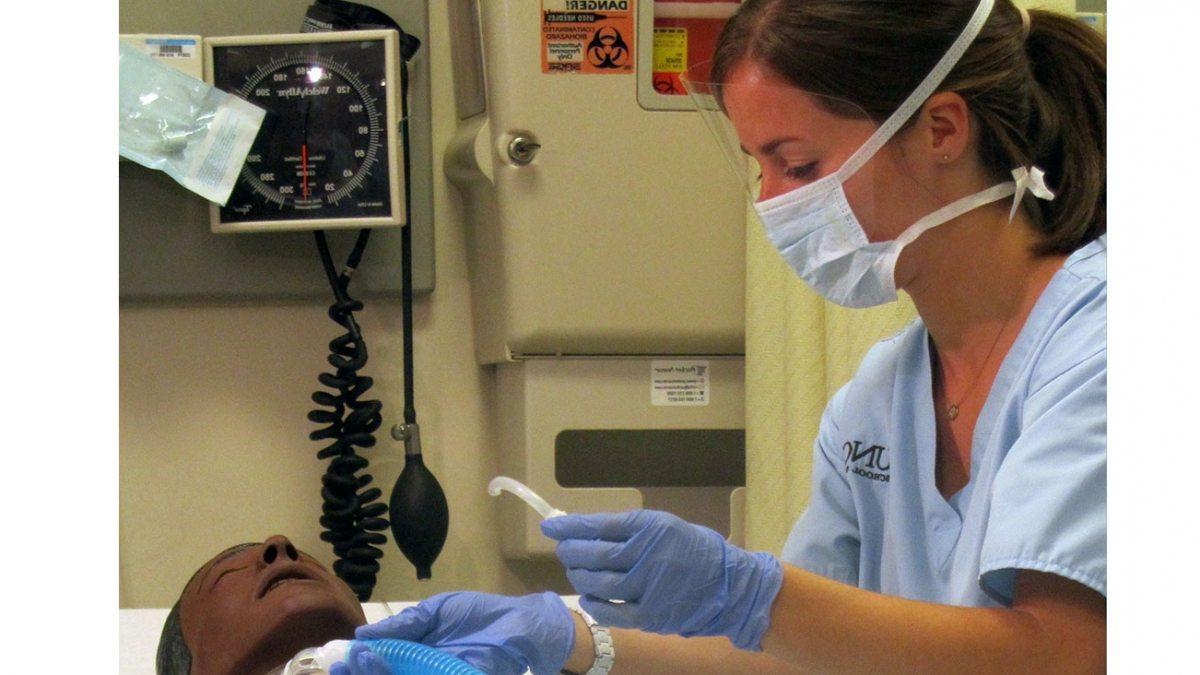 一个护理专业的学生在一个模拟病人身上工作.