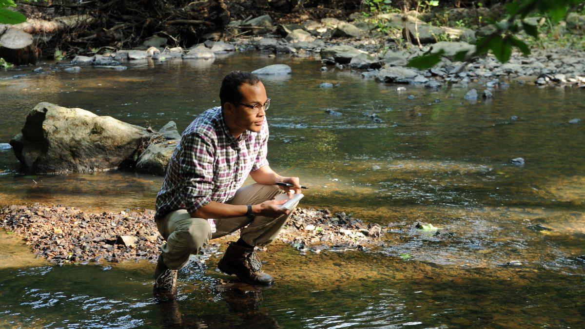 一个学生蹲在河边测试水质