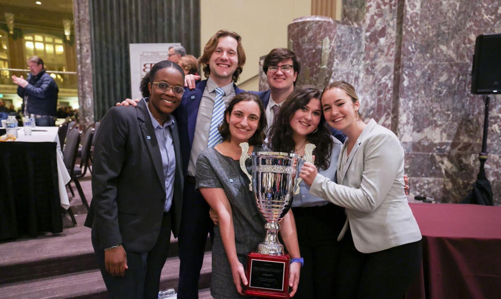 Six members of the UNC Ethics Bowl team posing with award in hands.